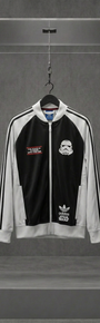 Jaqueta Adidas Originals x Star Wars preta com mangas brancas e estampa de Stormtrooper, em vitrine de acrílico