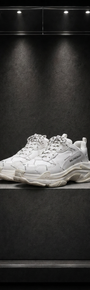 Tênis Balenciaga Triple S branco sobre pedestal, em vitrine de acrílico iluminada