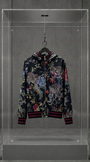 Jaqueta Dolce & Gabbana com estampa jungle de onças e flores sobre fundo escuro, em vitrine de acrílico