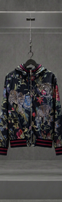 Jaqueta Dolce & Gabbana com estampa jungle de onças e flores sobre fundo escuro, em vitrine de acrílico