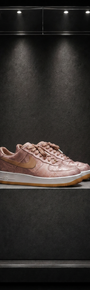 Tênis Nike Air Force 1 x CLOT Rose Gold Silk, em seda rosé com estampa jacquard, sobre pedestal em vitrine