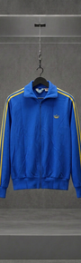 Jaqueta Adidas Trefoil vintage azul com listras amarelas nas mangas, gola alta, em vitrine de acrílico